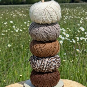 a tower of 50g balls of alpaca yarn in natural colours