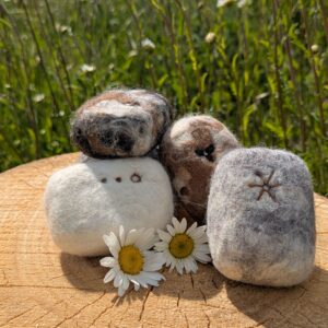 felted soaps on a wooden log in a field of daisies