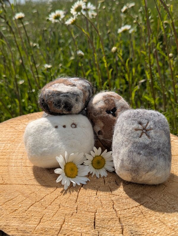 felted soaps on a wooden log in a field of daisies