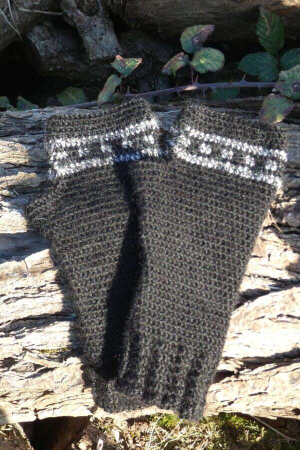 black wrist warmers with white stripe and dot detail on a log
