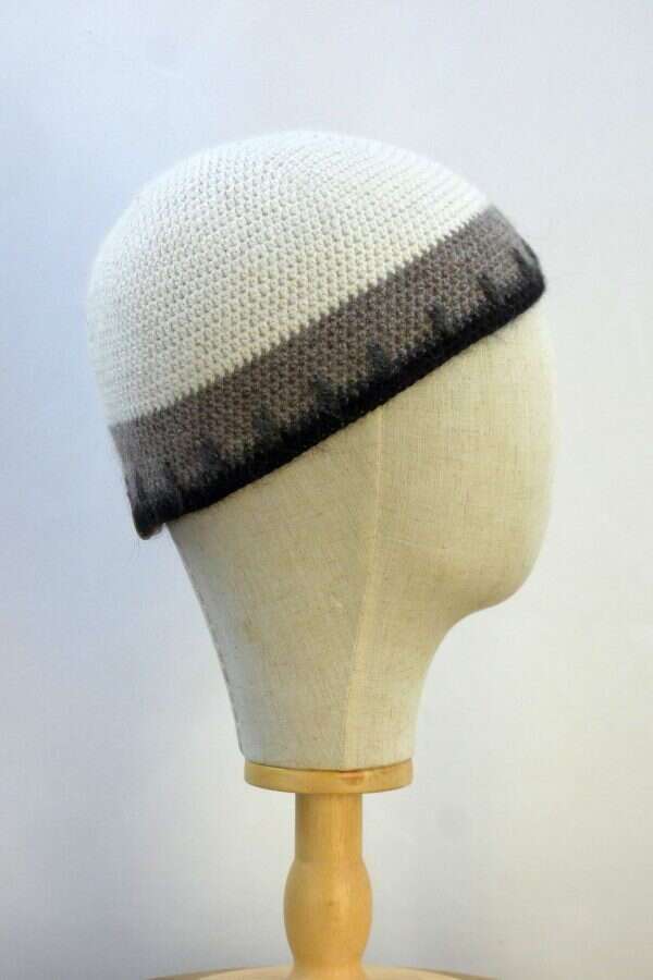 side view of a white, grey and black beanie hat displayed on a white display head