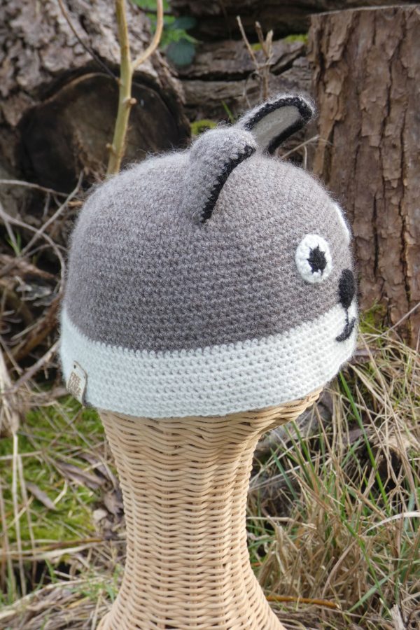 side view of a grey and white childs hat with a fox design made from alpaca yarn