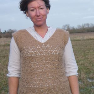 lady standing a field wearing a lacy crochet tank top in fawn alpaca yarn with a white shirt underneath