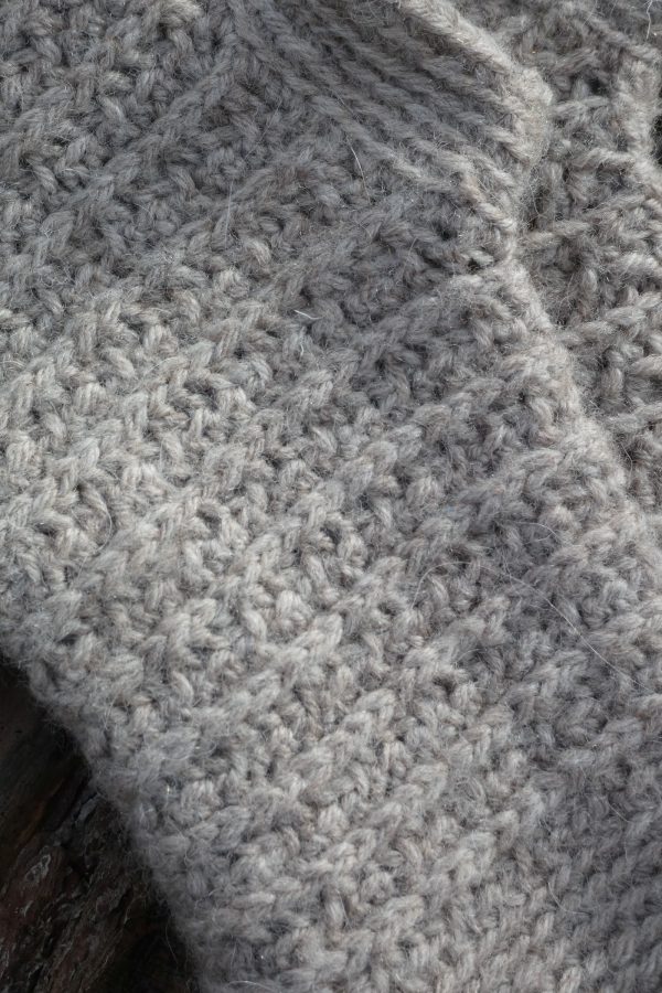 close up photo of light grey crochet wrist warmers with textured and ribbed pattern