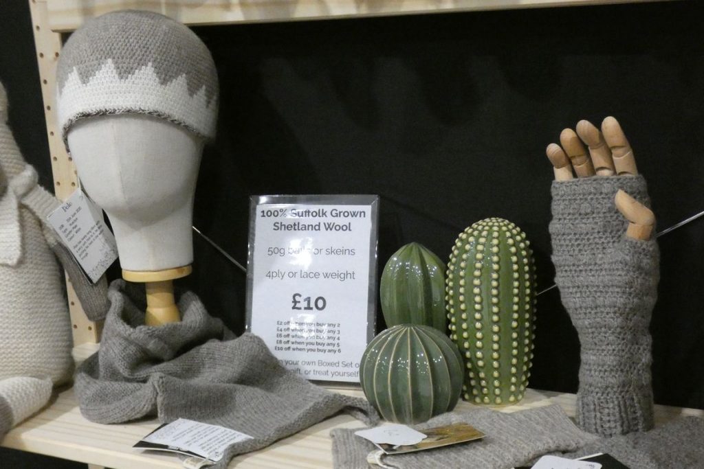 crochet products displayed on a wooden shelf with ceramic cacti