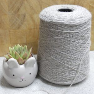 light grey laceweight shetland yarn on cone next to cactus plant in rabbit plant pot