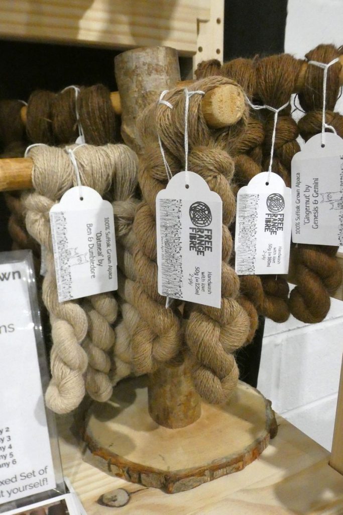 selection of brown alpaca yarn skeins on wooden display stand