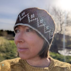 lady in yellow jumper wearing a brown and white tapestry crochet hat in shetland wool