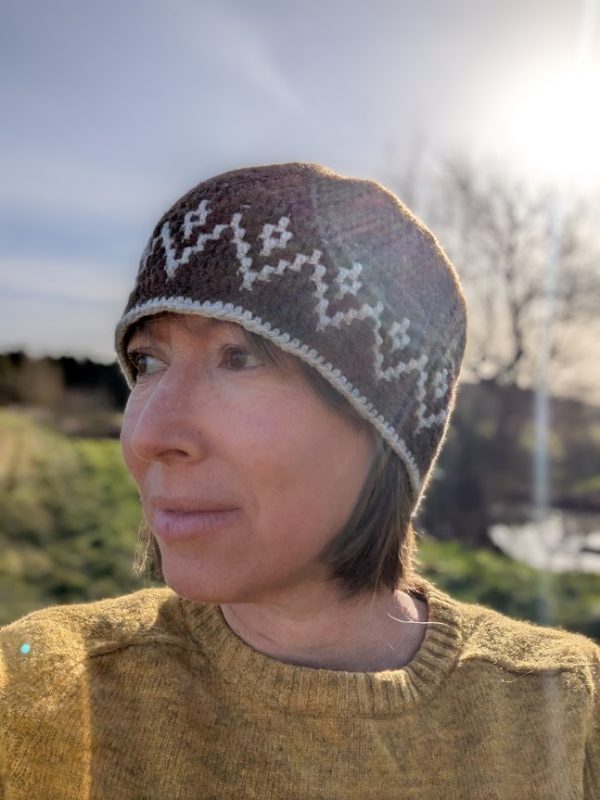 lady in yellow jumper wearing a brown and white tapestry crochet hat in shetland wool