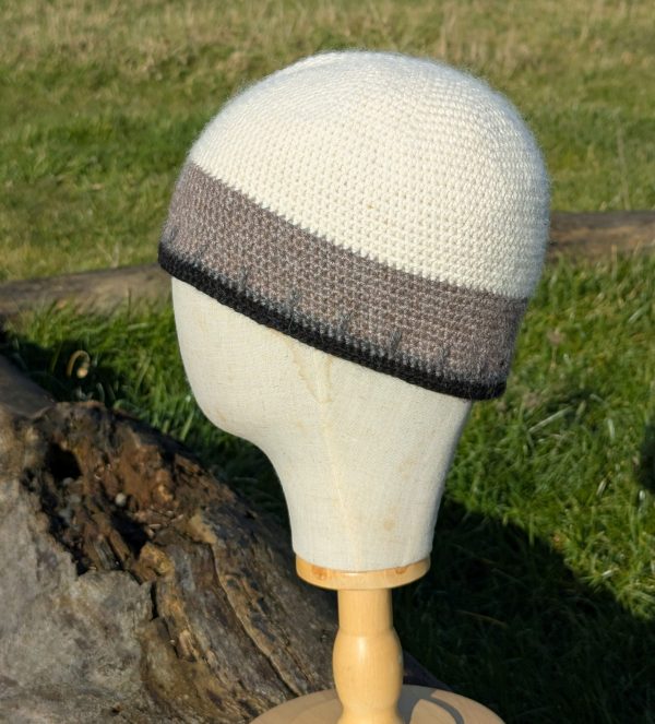 side view of a white black and grey alpaca beanie hat on a display head