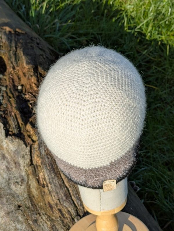 top view of a white grey and black alpaca beanie on a display head