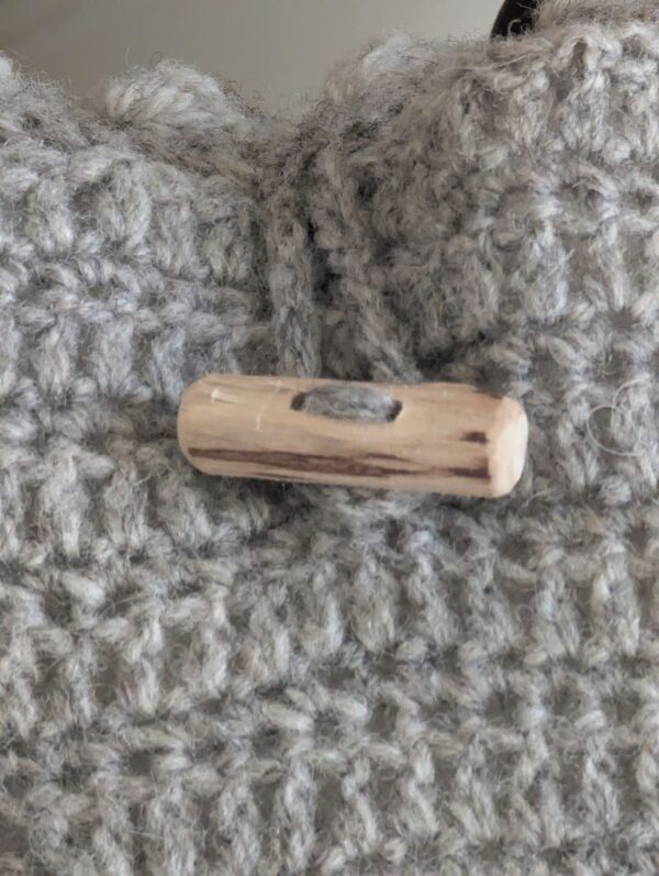 close up of wooden toggle on grey wool cushio